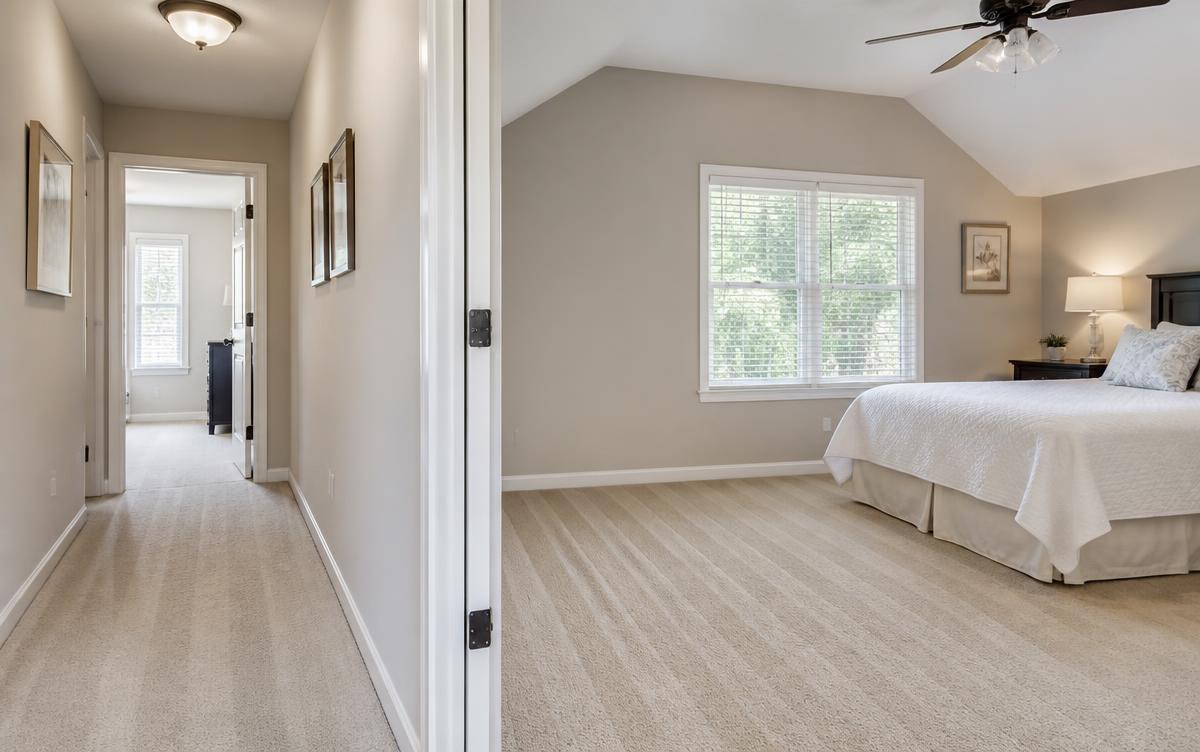 Freshly deep cleaned bedroom and hallway with vacuum lines on the carpet and dusted baseboards